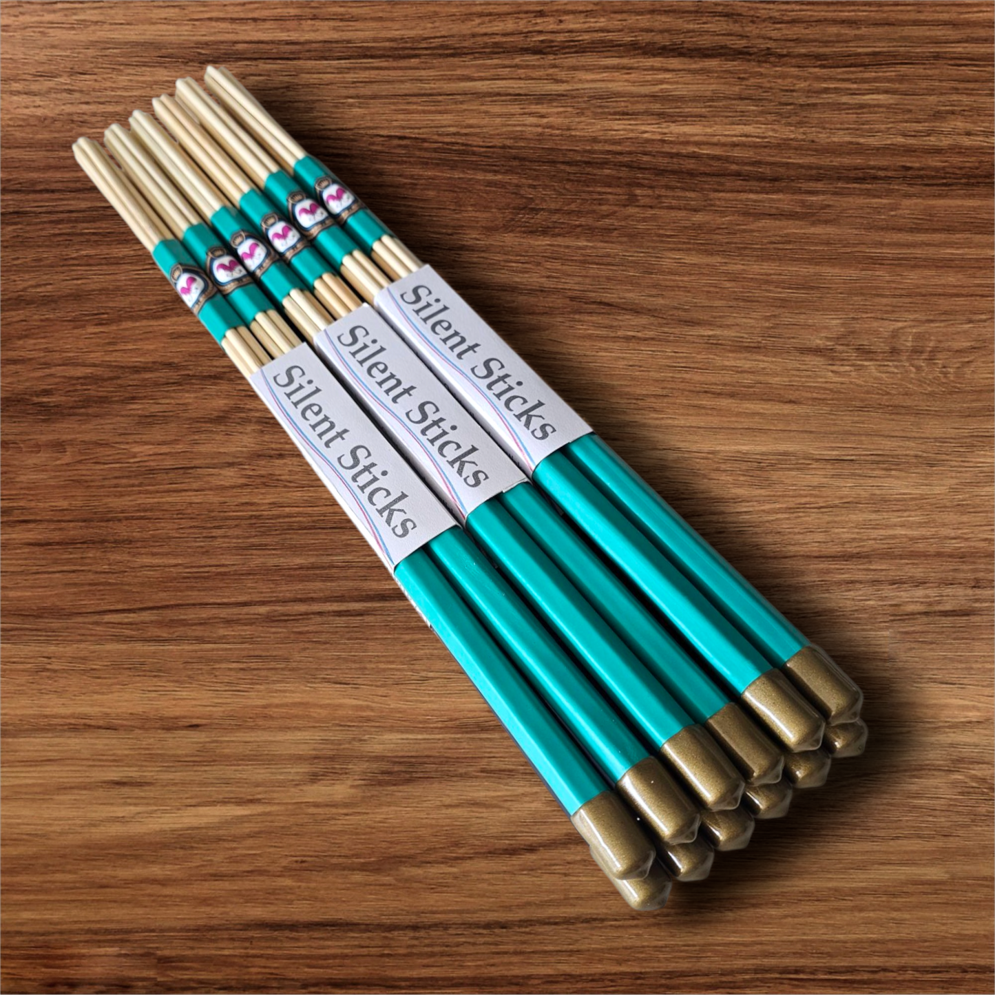 A brick containing 6 pairs of Silent Sticks 7-dowel hot rod drumsticks with green grip and gold end caps. Low volume practice drum rods for apartments and low-volume acoustic gigs.
