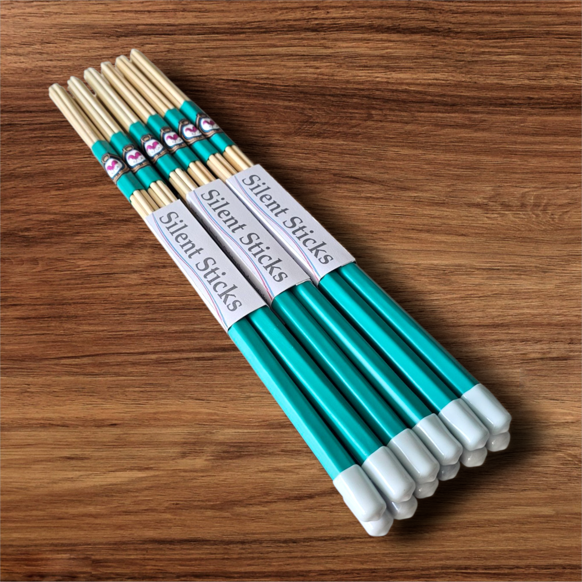 A brick containing 6 pairs of Silent Sticks 7-dowel hot rod drumsticks with green grip and white end caps. Low volume practice drum rods for apartments and low-volume acoustic gigs.