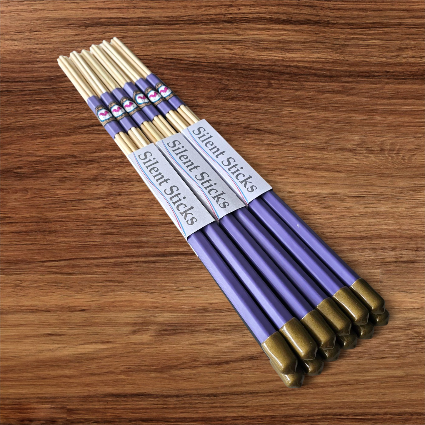 A brick containing 6 pairs of Silent Sticks 7-dowel hot rod drumsticks with purple grip and gold end caps. Low volume practice drum rods for apartments and low-volume acoustic gigs.