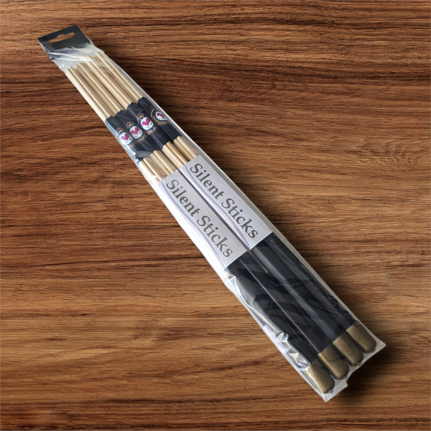 A package containing two pairs of custom Silent Sticks 7-dowel hot rod drumsticks with black grip and gold end caps. Low volume practice drum rods for apartments and low-volume acoustic gigs.