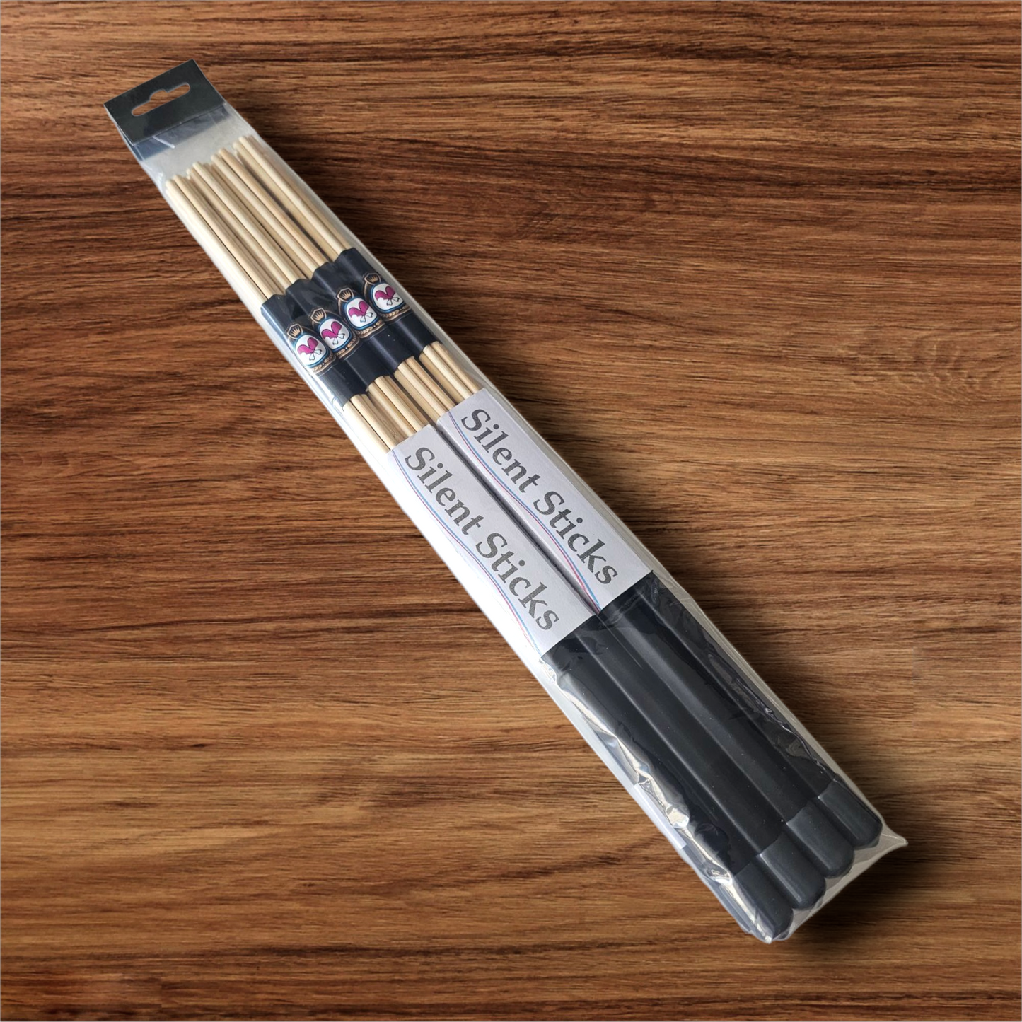 A package containing two pairs of custom Silent Sticks 7-dowel hot rod drumsticks with black grip and grey end caps. Low volume practice drum rods for apartments and low-volume acoustic gigs.