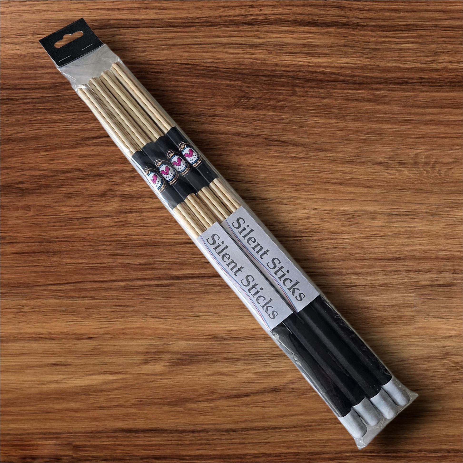 A package containing two pairs of custom Silent Sticks 7-dowel hot rod drumsticks with black grip and white end caps. Low volume practice drum rods for apartments and low-volume acoustic gigs.