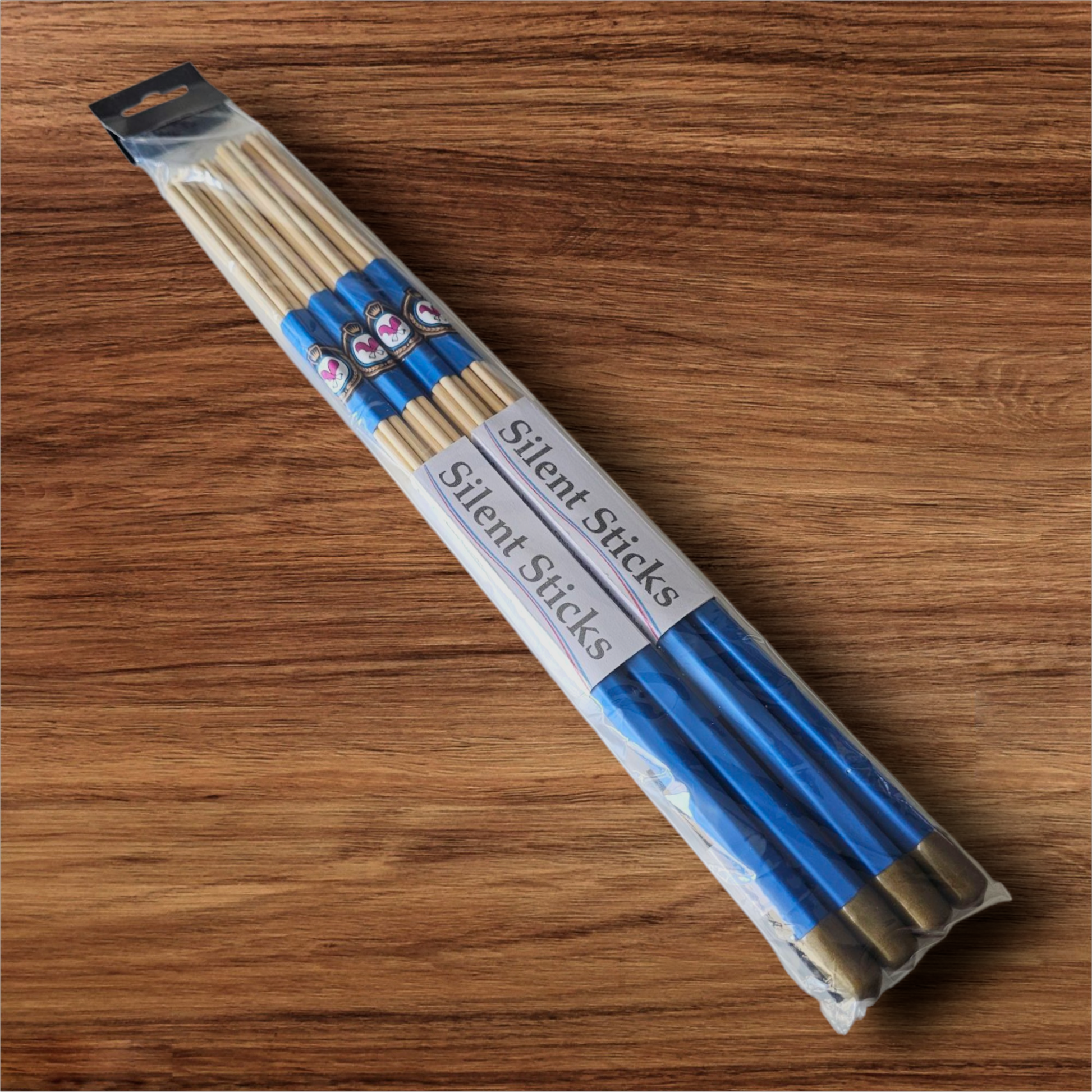 A package containing two pairs of custom Silent Sticks 7-dowel hot rod drumsticks with blue grip and gold end caps. Low volume practice drum rods for apartments and low-volume acoustic gigs.