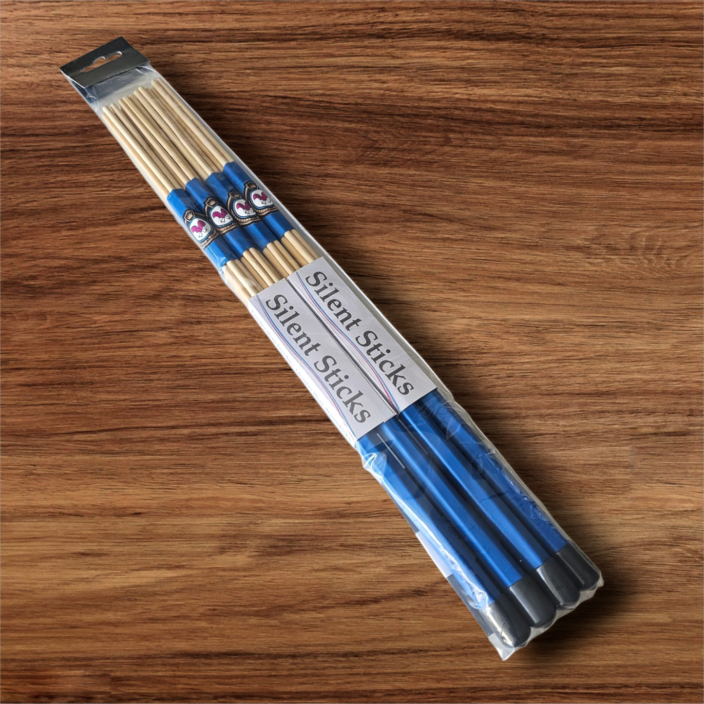 A package containing two pairs of custom Silent Sticks 7-dowel hot rod drumsticks with blue grip and grey end caps. Low volume practice drum rods for apartments and low-volume acoustic gigs.