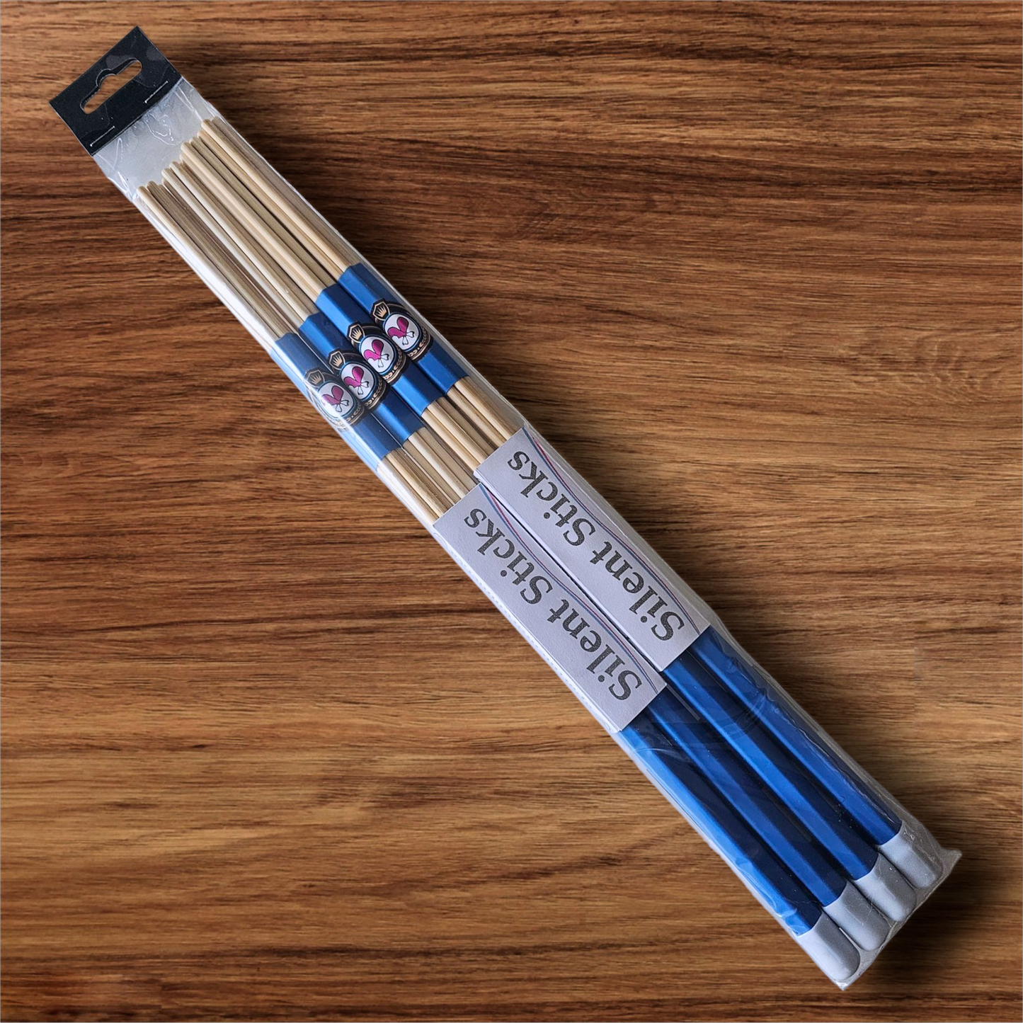 A package containing two pairs of custom Silent Sticks 7-dowel hot rod drumsticks with blue grip and white end caps. Low volume practice drum rods for apartments and low-volume acoustic gigs.