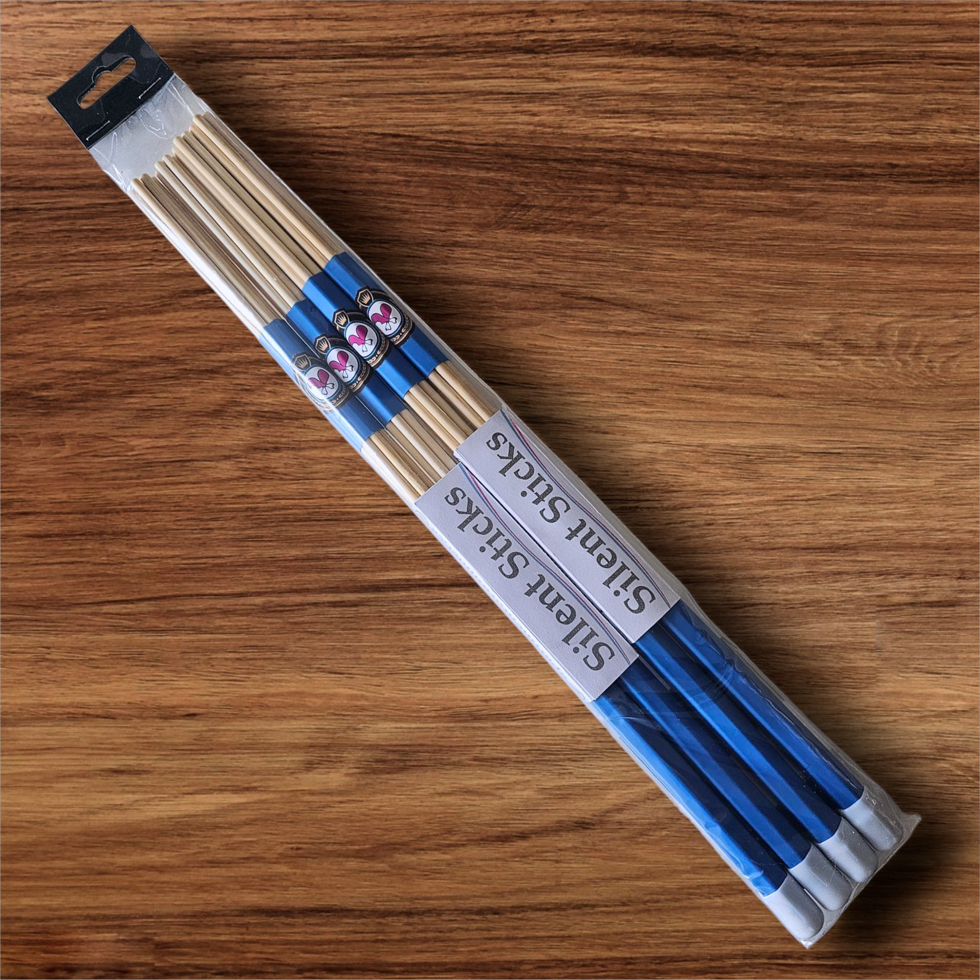 A package containing two pairs of custom Silent Sticks 7-dowel hot rod drumsticks with blue grip and white end caps. Low volume practice drum rods for apartments and low-volume acoustic gigs.