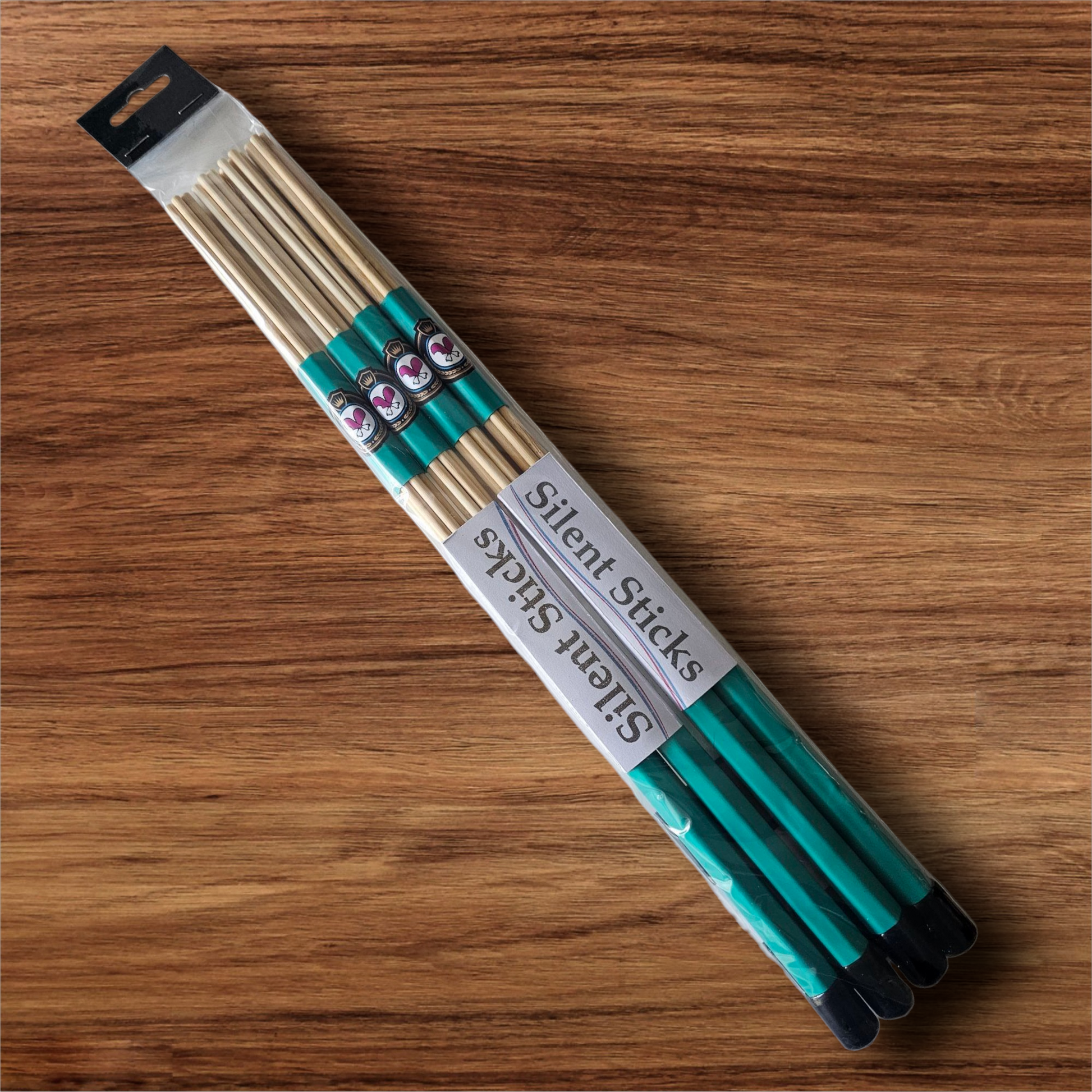 A package containing two pairs of custom Silent Sticks 7-dowel hot rod drumsticks with green grip and black end caps. Low volume practice drum rods for apartments and low-volume acoustic gigs.
