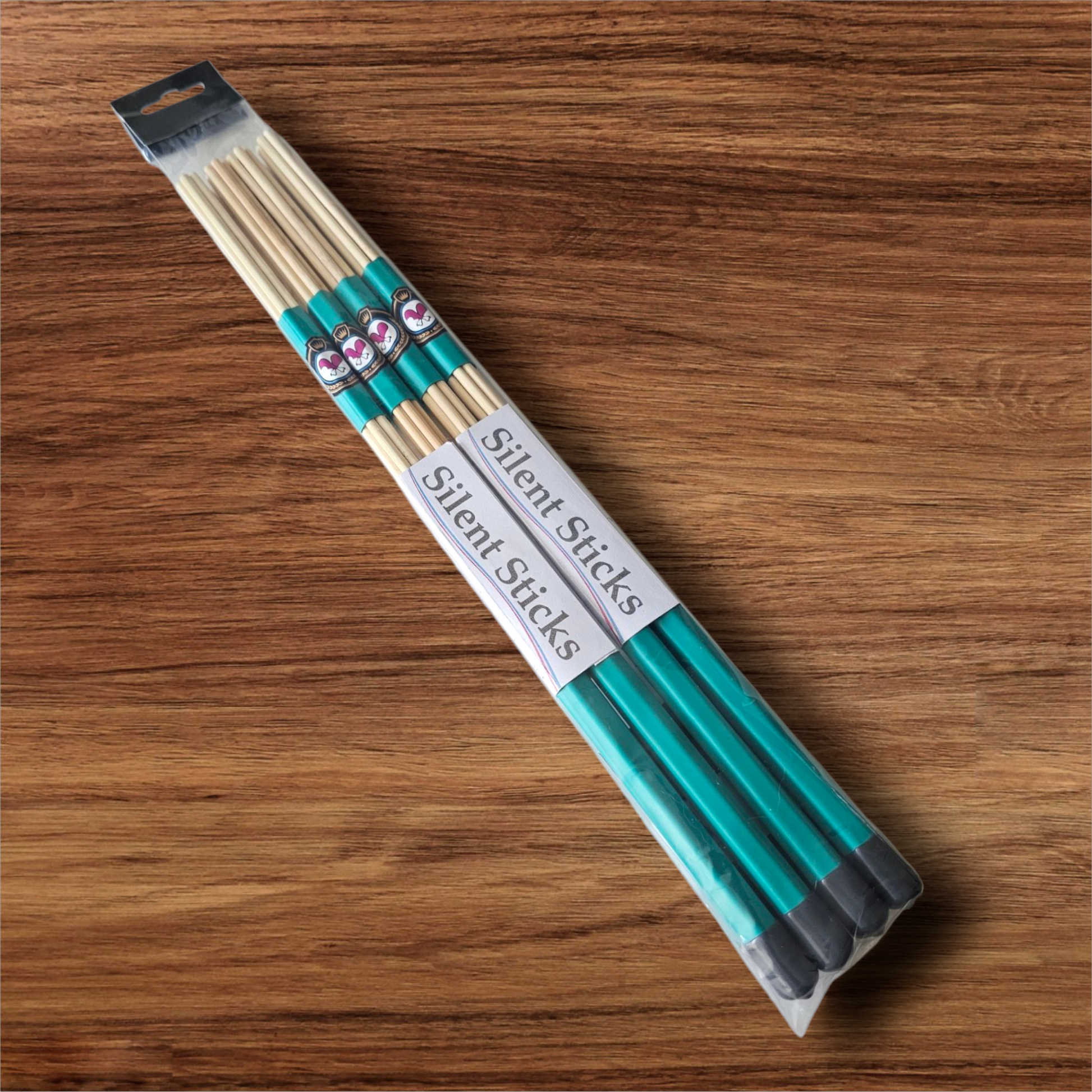A package containing two pairs of custom Silent Sticks 7-dowel hot rod drumsticks with green grip and gold end caps. Low volume practice drum rods for apartments and low-volume acoustic gigs.