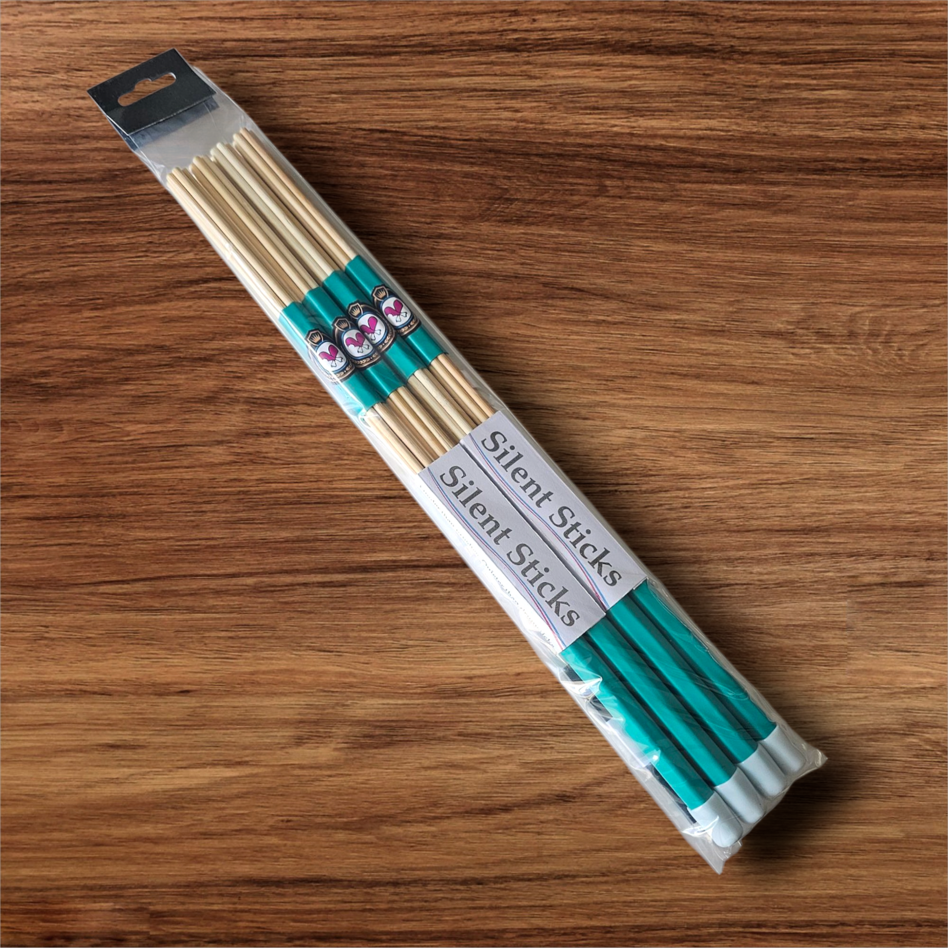 A package containing two pairs of custom Silent Sticks 7-dowel hot rod drumsticks with green grip and white end caps. Low volume practice drum rods for apartments and low-volume acoustic gigs.