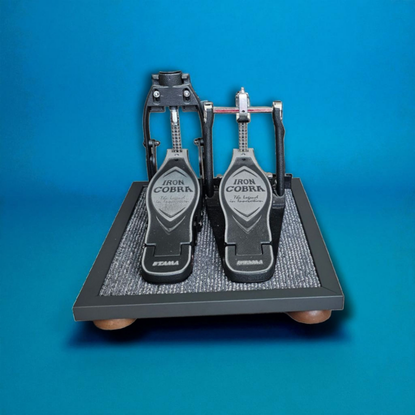 A grey Silent Stomper impact noise isolation platform (double pedal for hi-hat pedals and double bass drum pedals) designed for drummers, enabling quiet practice in enclosed spaces like apartment buildings by reducing vibrations and preventing noise disturbances/complaints for neighbors.