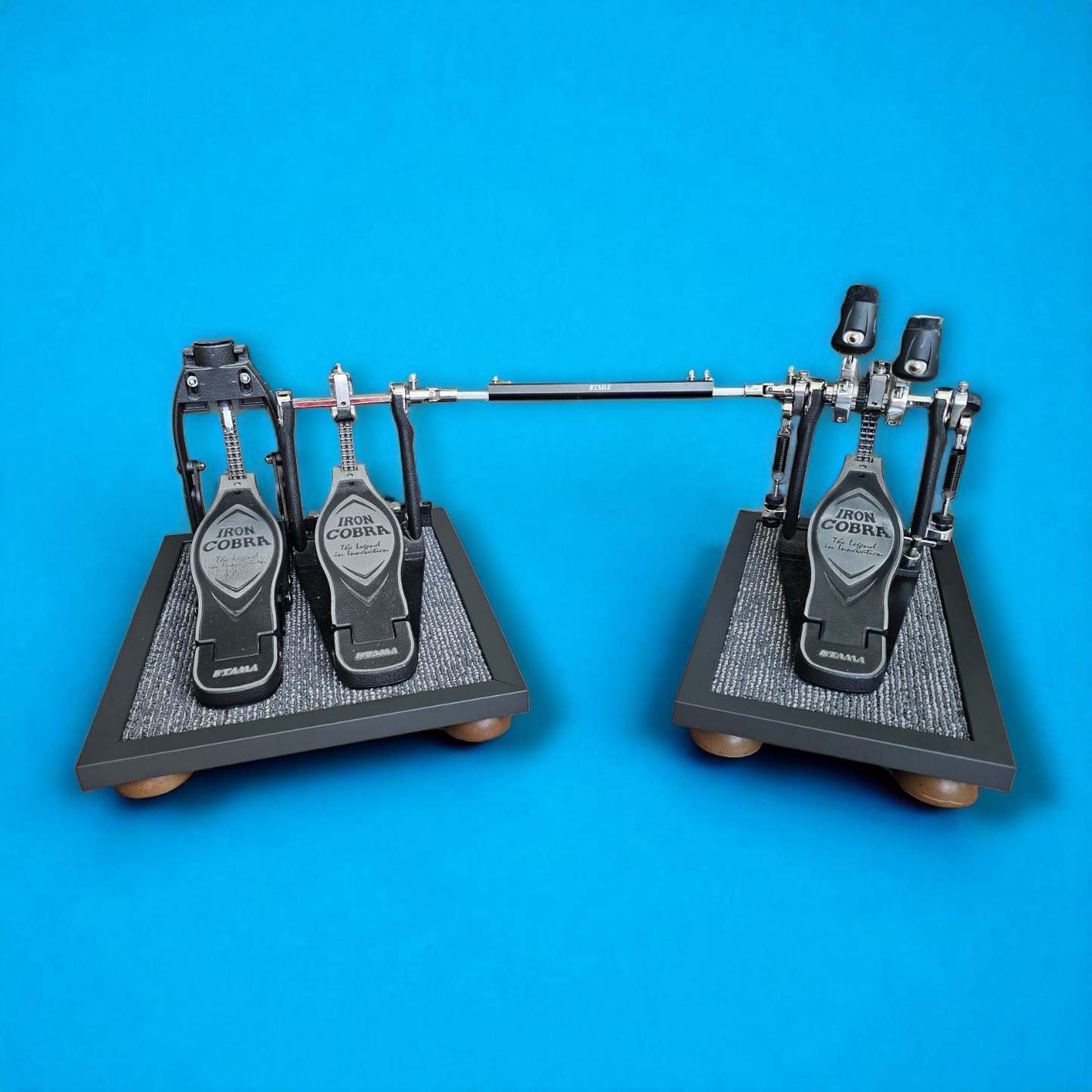 A pair of grey Silent Stomper impact noise isolation platforms (single pedal and double pedal pack - for hi-hat pedals and double bass drum pedals) designed for drummers, enabling quiet practice in enclosed spaces like apartment buildings by reducing vibrations and preventing noise disturbances/complaints for neighbors.
