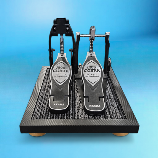 Carbon fiber double pedal Silent Stomper impact noise isolation platform designed for drummers, enabling quiet practice in enclosed spaces like apartment buildings by reducing/eliminating vibrations and preventing noise disturbances for neighbors.