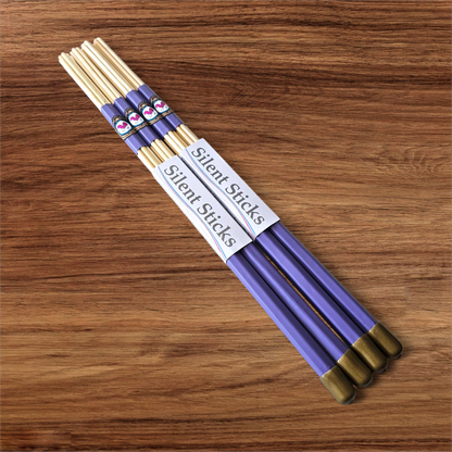 A package containing two pairs of custom Silent Sticks 7-dowel hot rod drumsticks with purple grip and gold end caps. Low volume practice drum rods for apartments and low-volume acoustic gigs.